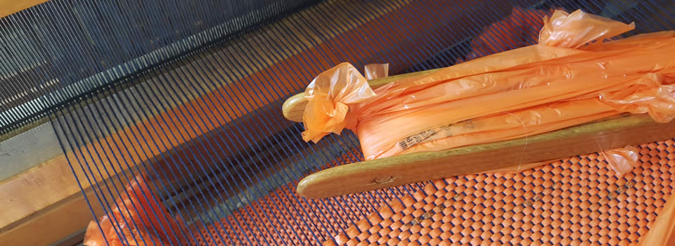 Orange weft on loom with shuttle.
